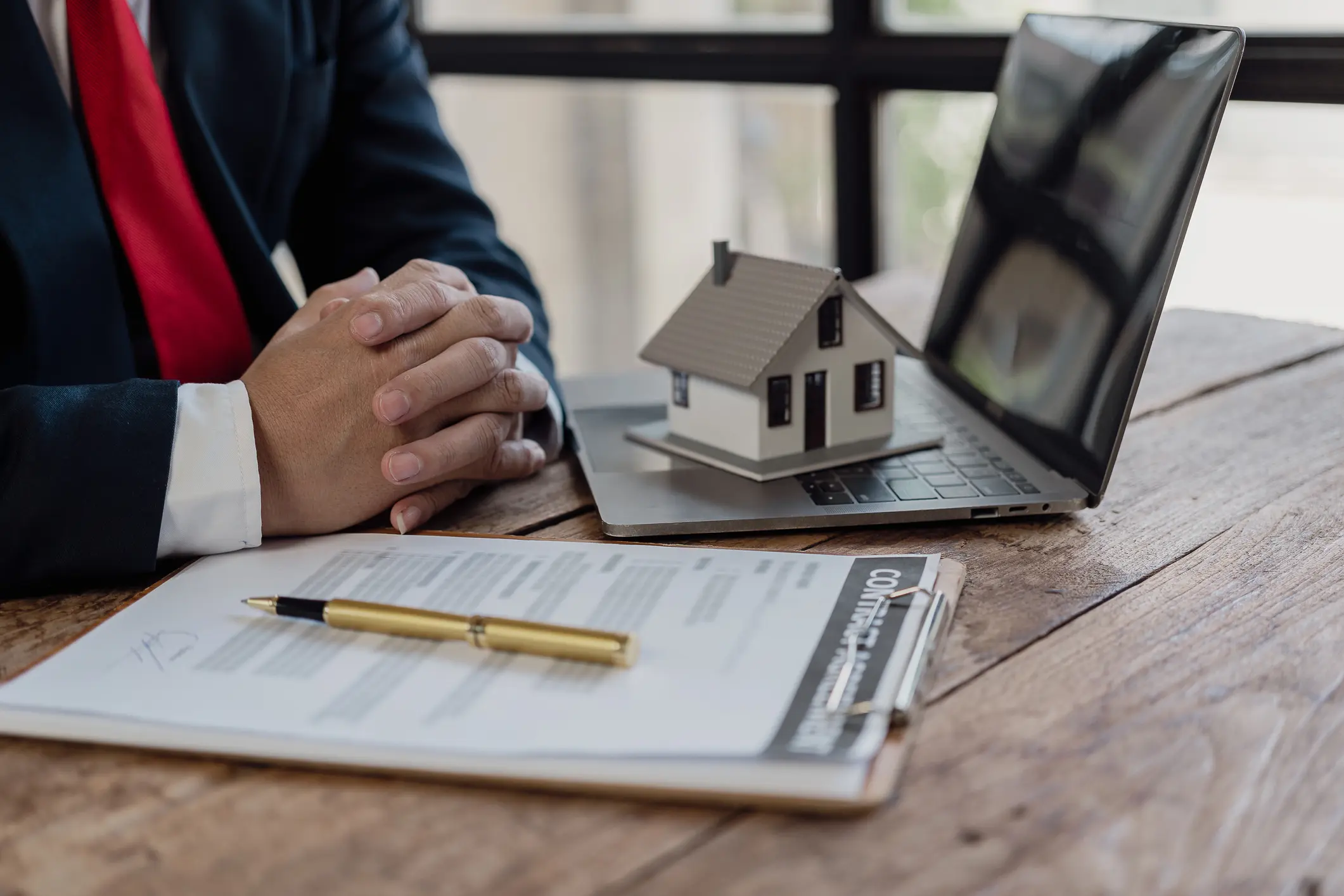 Person reviewing house model and documents on a desk.
