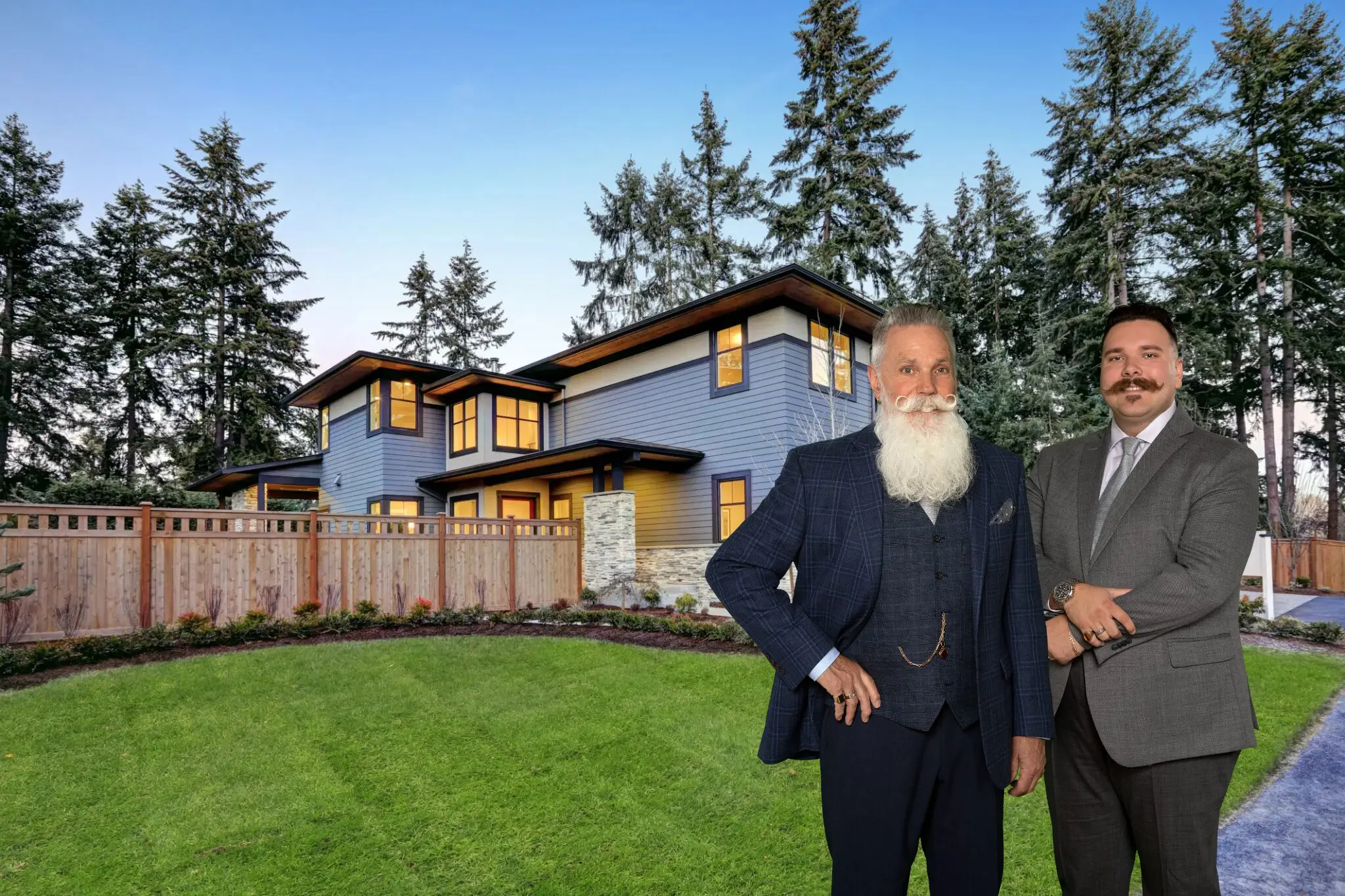 Two men in suits posing in front of a modern house with a wooden deck and lush lawn.