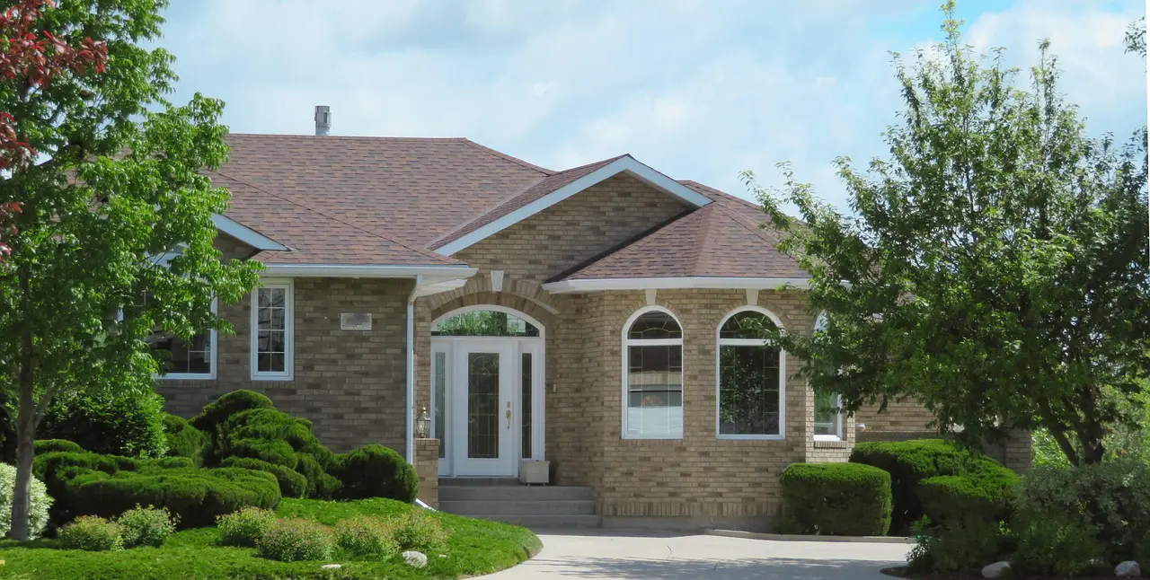 Modern brick house with arched windows and a green lawn.