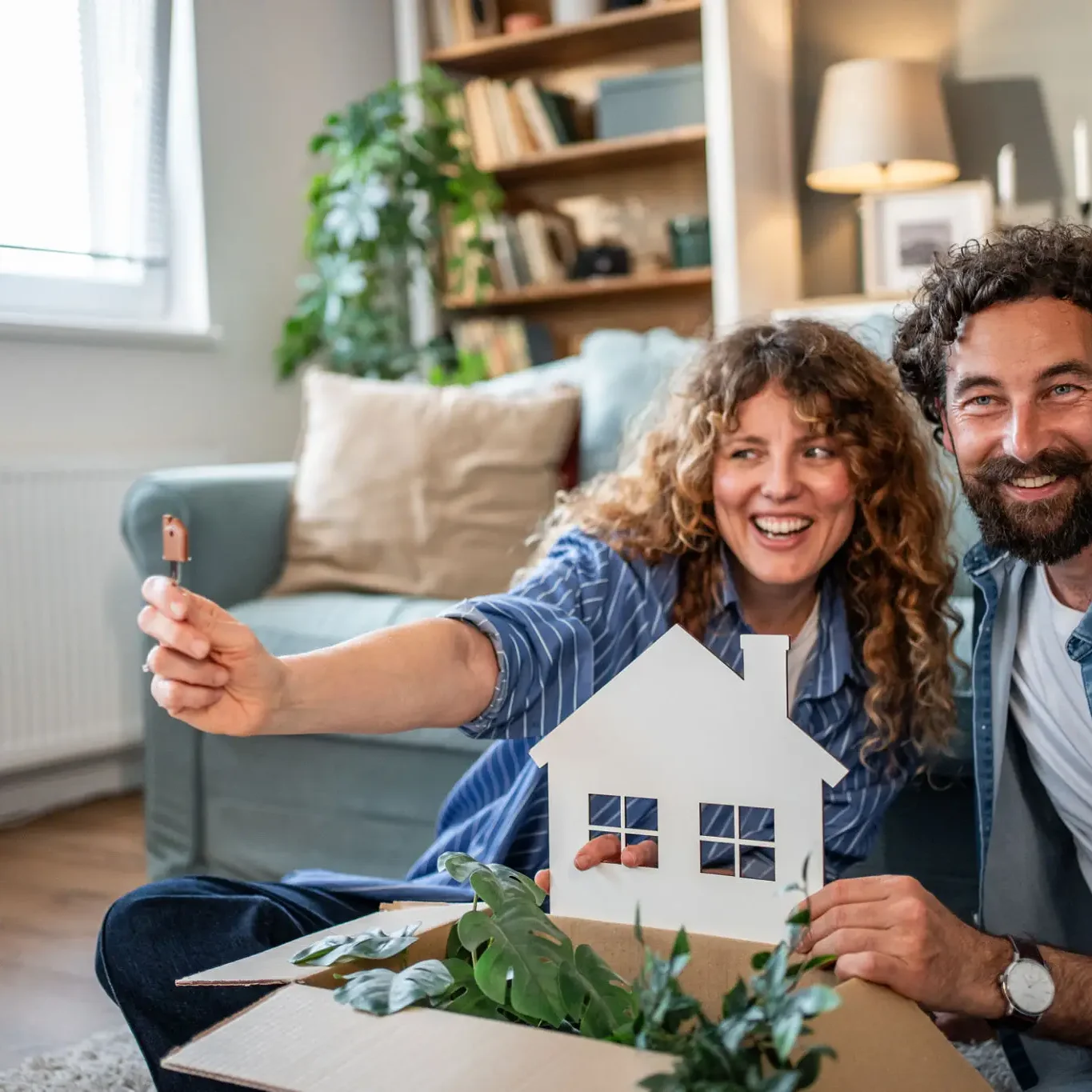 Happy couple holding a small house model, celebrating a new home.